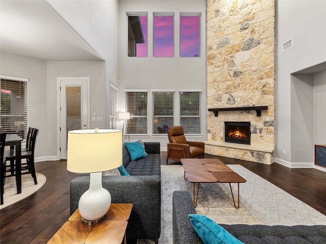 living room featuring baseboards, a fireplace, visible vents, and dark wood-type flooring