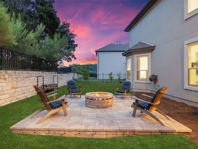 patio terrace at dusk featuring an outdoor fire pit and a fenced backyard