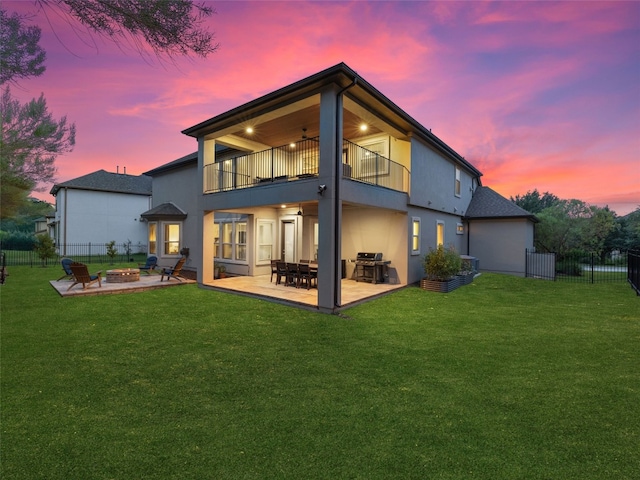 back of property at dusk featuring an outdoor fire pit, a patio, a balcony, and stucco siding