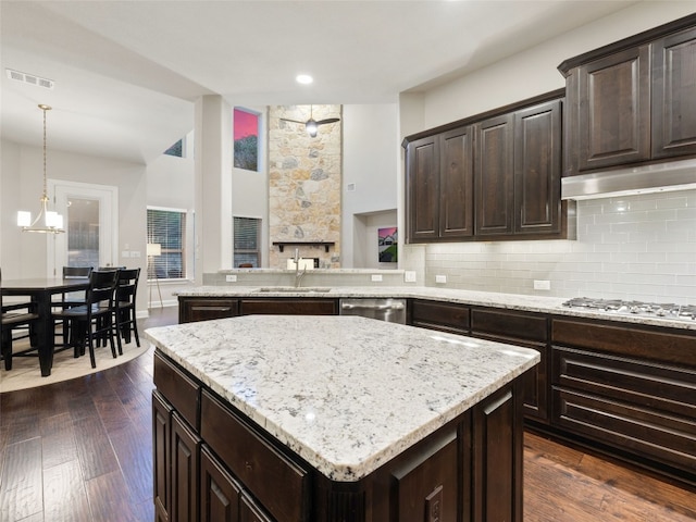 3417 Flat Iron Ct, Leander, TX 78641 - kitchen with appliances with stainless steel finishes, light stone countertops, backsplash, under cabinet range hood, and a kitchen island