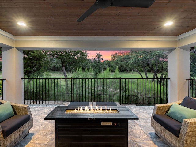 patio terrace at dusk featuring an outdoor fire pit, ceiling fan, and fence