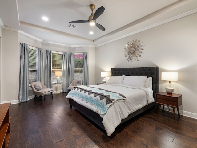 bedroom featuring dark wood-style floors, visible vents, a tray ceiling, and baseboards