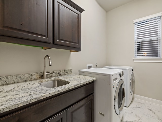 laundry area featuring cabinet space, baseboards, marble finish floor, separate washer and dryer, and a sink