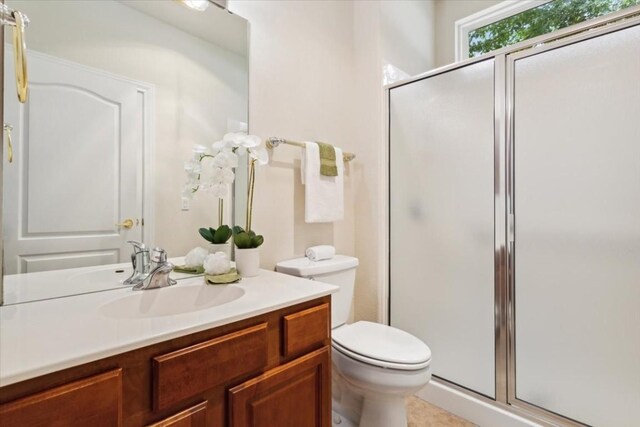 bathroom featuring a shower with shower door, vanity, and toilet