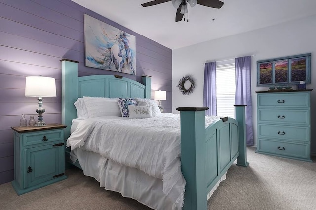 carpeted bedroom featuring ceiling fan and wooden walls