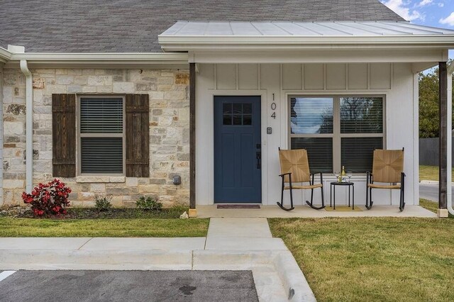 view of exterior entry featuring a lawn