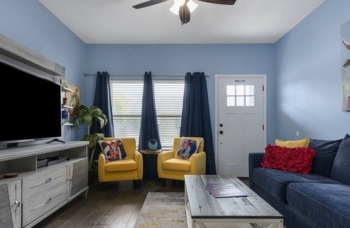 living room with ceiling fan, plenty of natural light, and dark hardwood / wood-style flooring