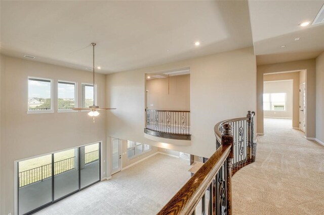 hallway with a wealth of natural light and light colored carpet