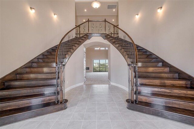 staircase with light tile patterned floors and a high ceiling