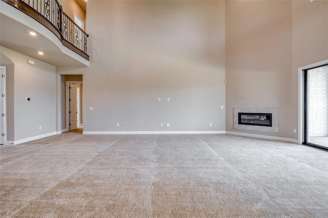 unfurnished living room featuring carpet and a towering ceiling