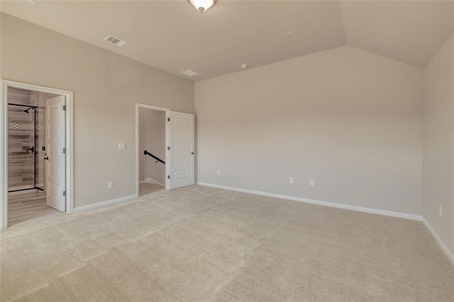 unfurnished bedroom with ensuite bathroom, light colored carpet, and vaulted ceiling