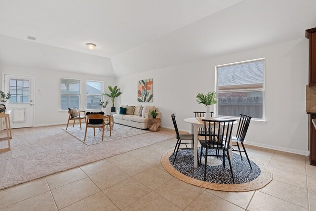 tiled dining room featuring vaulted ceiling