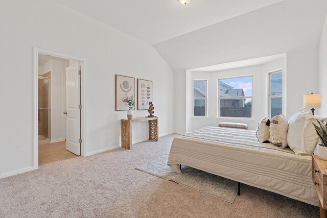 bedroom with light colored carpet, ensuite bath, and vaulted ceiling