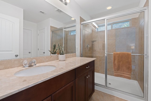 bathroom featuring walk in shower, vanity, and tile patterned flooring