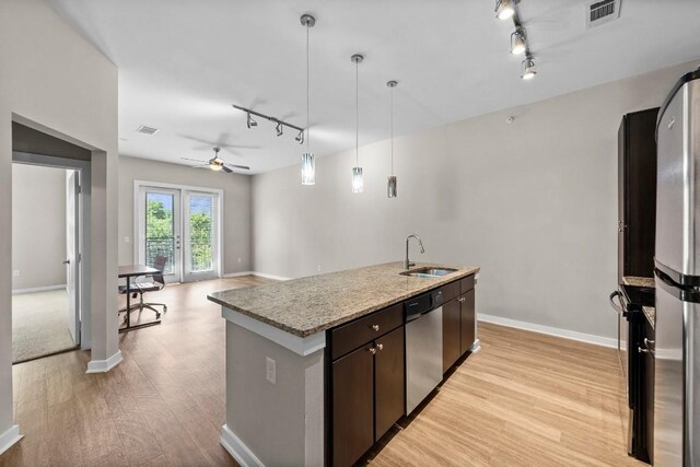 kitchen featuring appliances with stainless steel finishes, pendant lighting, an island with sink, sink, and dark brown cabinets