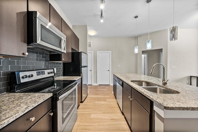 kitchen with backsplash, appliances with stainless steel finishes, light wood-style floors, a sink, and dark brown cabinetry