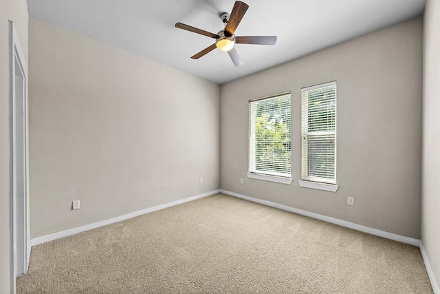 spare room with light carpet, ceiling fan, and baseboards