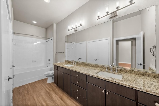 full bathroom with toilet, wood finished floors, a sink, and shower / tub combination