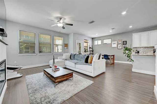 living room featuring dark hardwood / wood-style flooring, ceiling fan, and a wealth of natural light