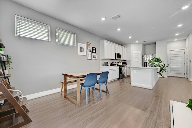 kitchen with white cabinets, appliances with stainless steel finishes, light wood-type flooring, and a center island