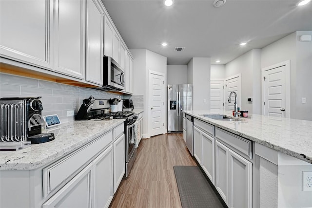 kitchen with light hardwood / wood-style floors, sink, stainless steel appliances, and white cabinets