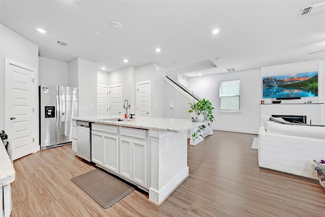 kitchen with white cabinetry, stainless steel appliances, light wood-type flooring, a kitchen island with sink, and sink