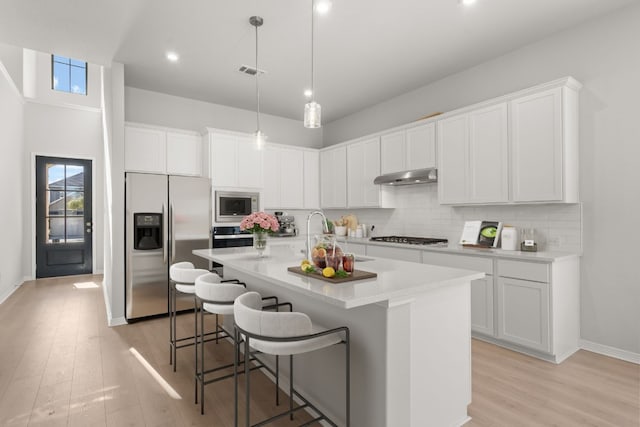 kitchen with a breakfast bar, white cabinetry, stainless steel appliances, and a kitchen island with sink