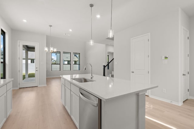 kitchen featuring a kitchen island with sink, white cabinets, sink, stainless steel dishwasher, and light hardwood / wood-style floors