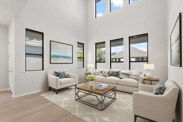 living room featuring a high ceiling, light hardwood / wood-style flooring, and a healthy amount of sunlight