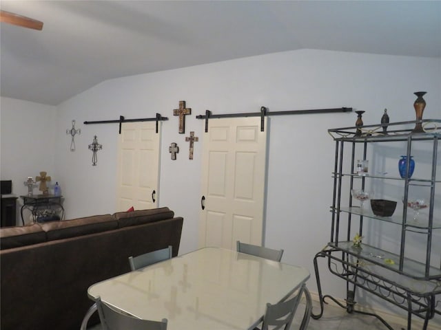 dining room with a barn door and lofted ceiling