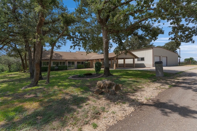 single story home featuring a garage, an outbuilding, and a front lawn