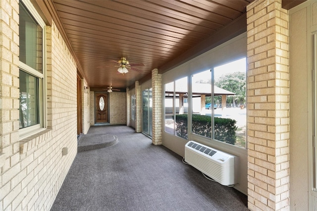 unfurnished sunroom featuring ceiling fan, heating unit, and wooden ceiling