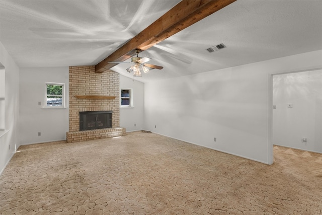 unfurnished living room with carpet flooring, ceiling fan, brick wall, a fireplace, and lofted ceiling with beams