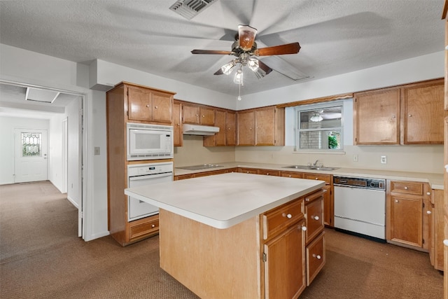 kitchen featuring ceiling fan, white appliances, sink, a center island, and carpet