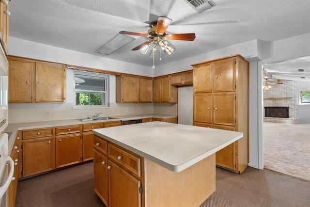 kitchen with a fireplace, ceiling fan, a center island, dark carpet, and a textured ceiling