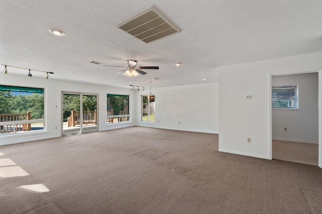 spare room featuring carpet floors, rail lighting, a textured ceiling, and ceiling fan