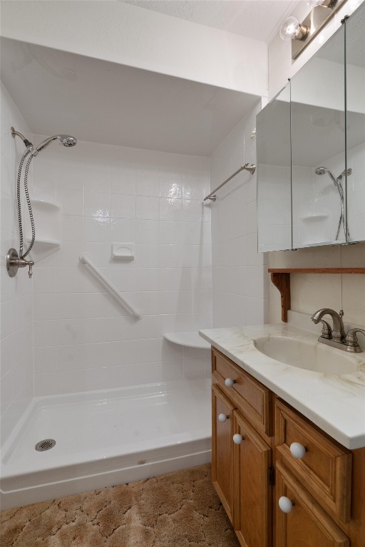 bathroom with tiled shower and vanity