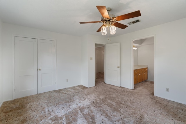 unfurnished bedroom featuring ensuite bathroom, a closet, and ceiling fan