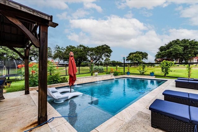 view of swimming pool featuring pool water feature, a trampoline, a patio area, and a lawn