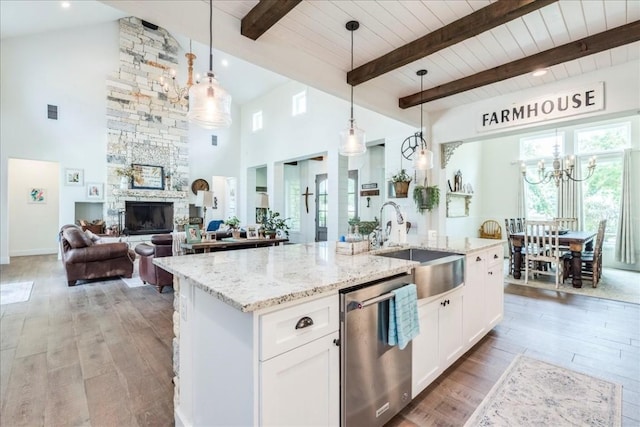 kitchen with white cabinets, light hardwood / wood-style floors, stainless steel dishwasher, and hanging light fixtures