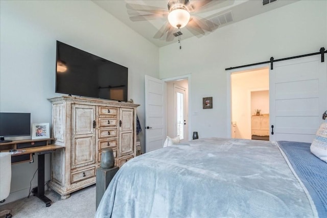 carpeted bedroom with ceiling fan and a barn door