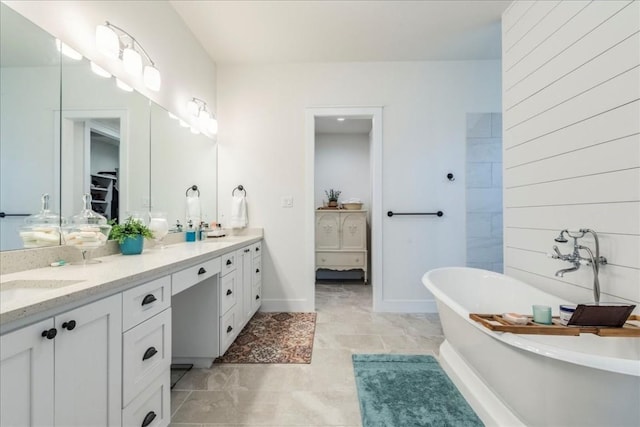 bathroom featuring tile patterned floors, a washtub, and vanity