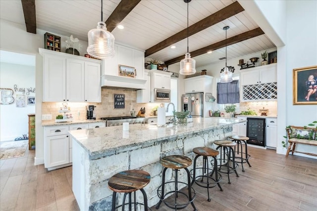 kitchen with wine cooler, white cabinetry, stainless steel appliances, and hanging light fixtures