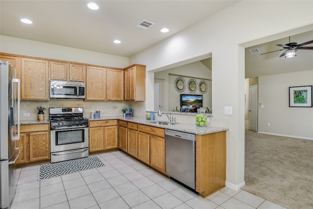 kitchen featuring light carpet, decorative backsplash, light stone counters, appliances with stainless steel finishes, and sink