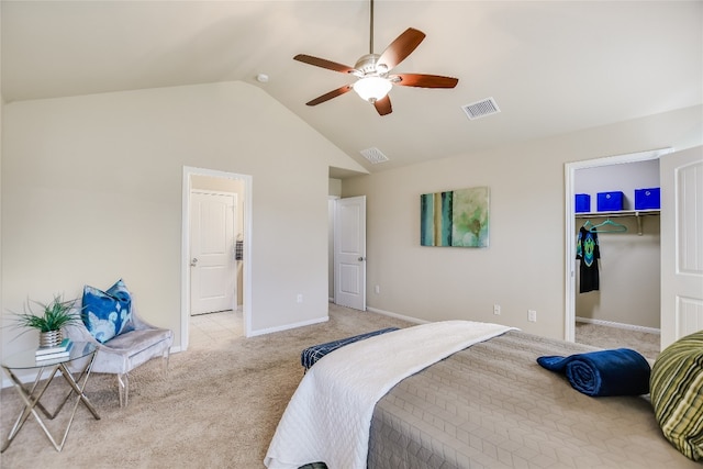 bedroom with vaulted ceiling, light carpet, a walk in closet, and ceiling fan