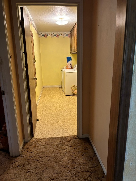 hallway featuring washing machine and clothes dryer, a textured ceiling, and carpet flooring