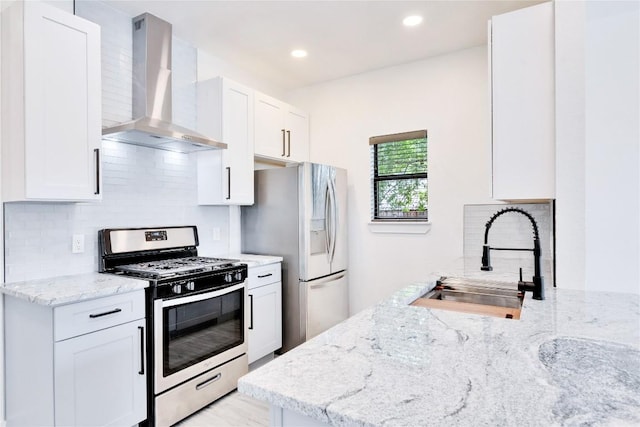 314 Saxon Ln, Austin, TX 78741 - kitchen featuring stainless steel appliances, wall chimney exhaust hood, light stone counters, backsplash, and white cabinets