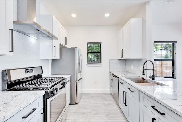 314 Saxon Ln, Austin, TX 78741 - kitchen with stainless steel appliances, wall chimney range hood, light wood finished floors, light stone countertops, and recessed lighting