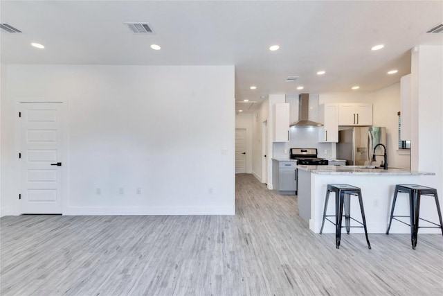 314 Saxon Ln, Austin, TX 78741 - kitchen with wall chimney exhaust hood, stainless steel fridge, a breakfast bar area, light wood-style floors, and range