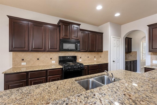 kitchen featuring light stone counters, sink, black appliances, and dark brown cabinetry